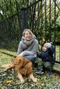 秋日里，妇女和幼儿带着金毛猎犬在公园享受欢乐
