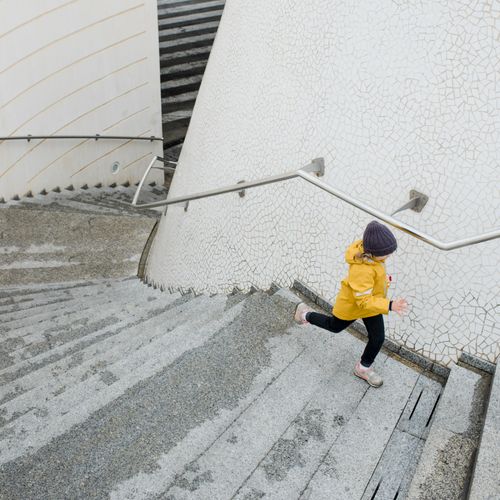 Child in a yellow jacket running up concrete steps — photo by Ksenia Chernaya on Pexels