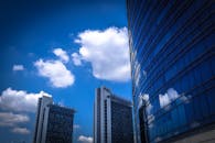 现代摩天大楼映衬着明亮的蓝天，白云倒映，景色令人惊叹