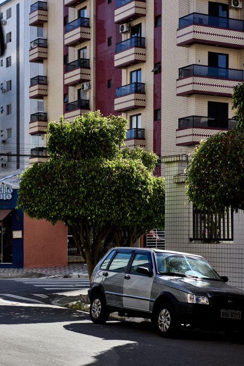 Free Sunny urban street with a parked car and apartment buildings in the background. Stock Photo