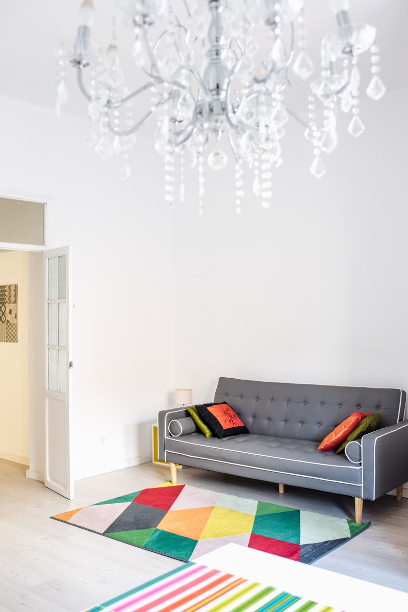 A gray couch with colorful cushions and geometric rug in a bright room