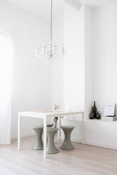 A minimalist interior room with white walls, a chandelier, and simple decor