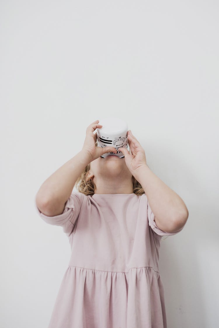 Adorable Little Girl Drinking Cup Of Milk