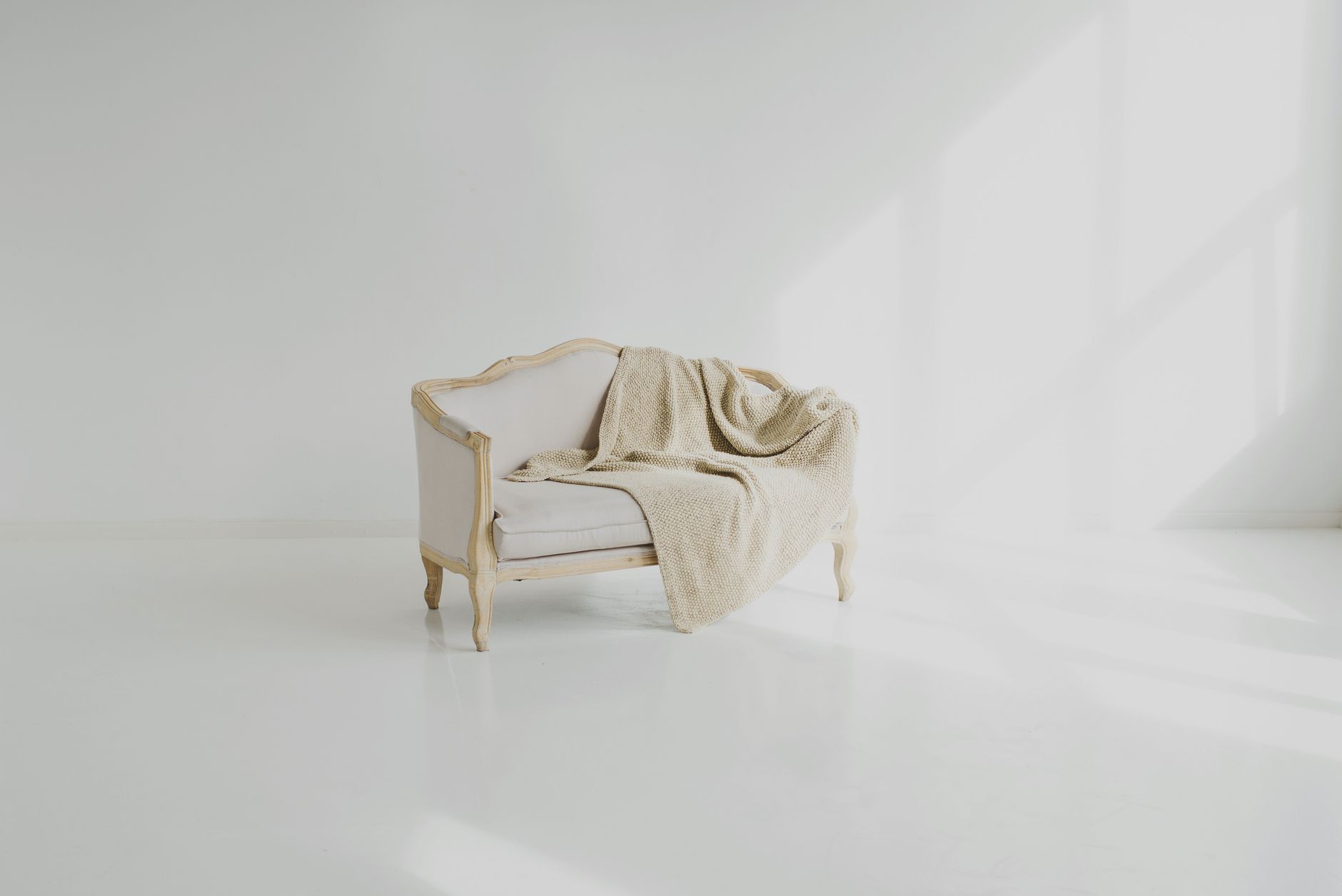 warm minimal interior with beige sofa and sunlight on a white wall
