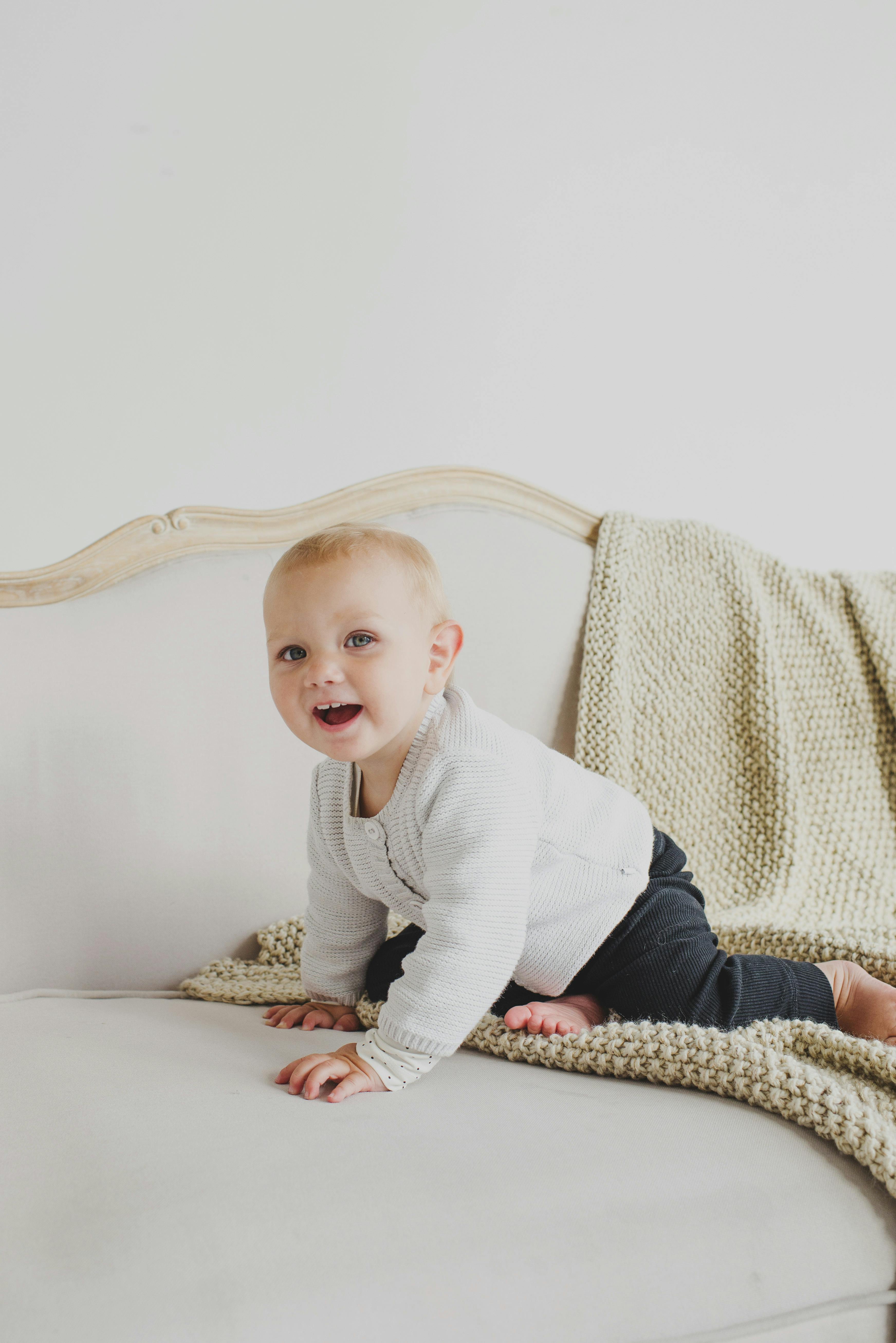 cute infant baby sitting on sofa and smiling