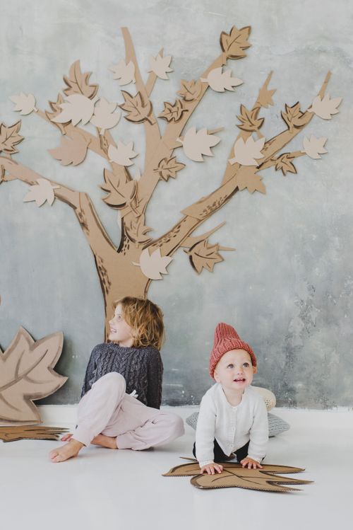 Free Kids having fun indoors with cardboard cutout tree, promoting creativity and family time. Stock Photo