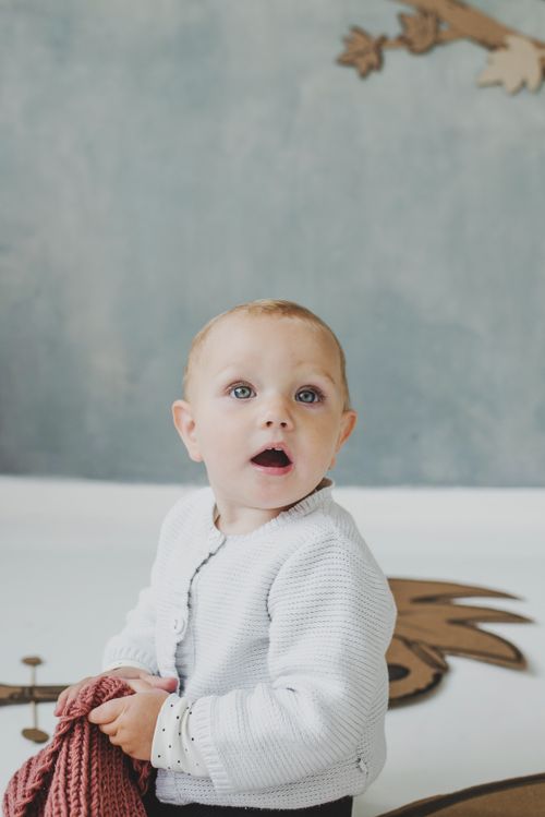 Free Cute baby with open mouth wearing a knitted sweater inside a studio. Stock Photo