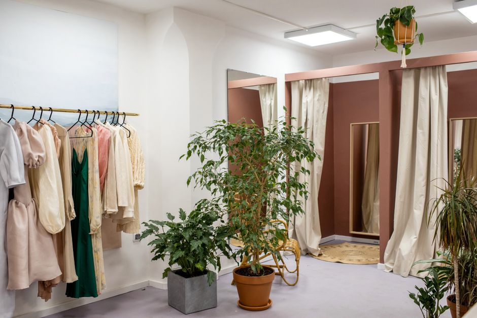 Stylish boutique interior showcasing elegant garments on rack with green plants.
