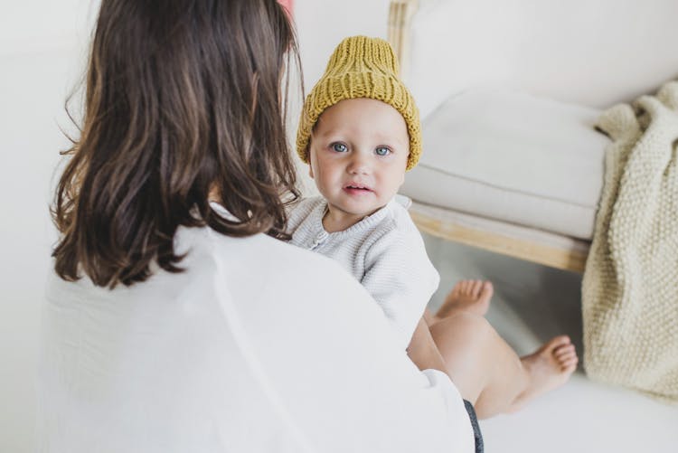 Mother Holding A Cute Baby In A Knitted Beanie 