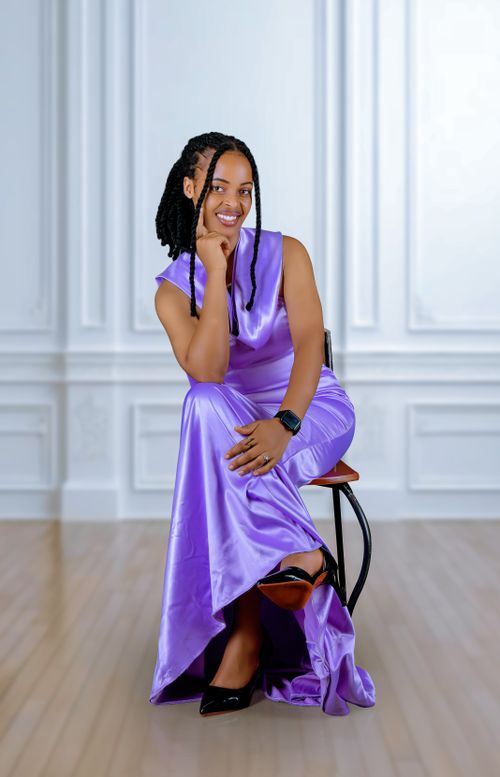 Free A woman in a stylish purple dress sitting elegantly against a white backdrop indoors. Stock Photo