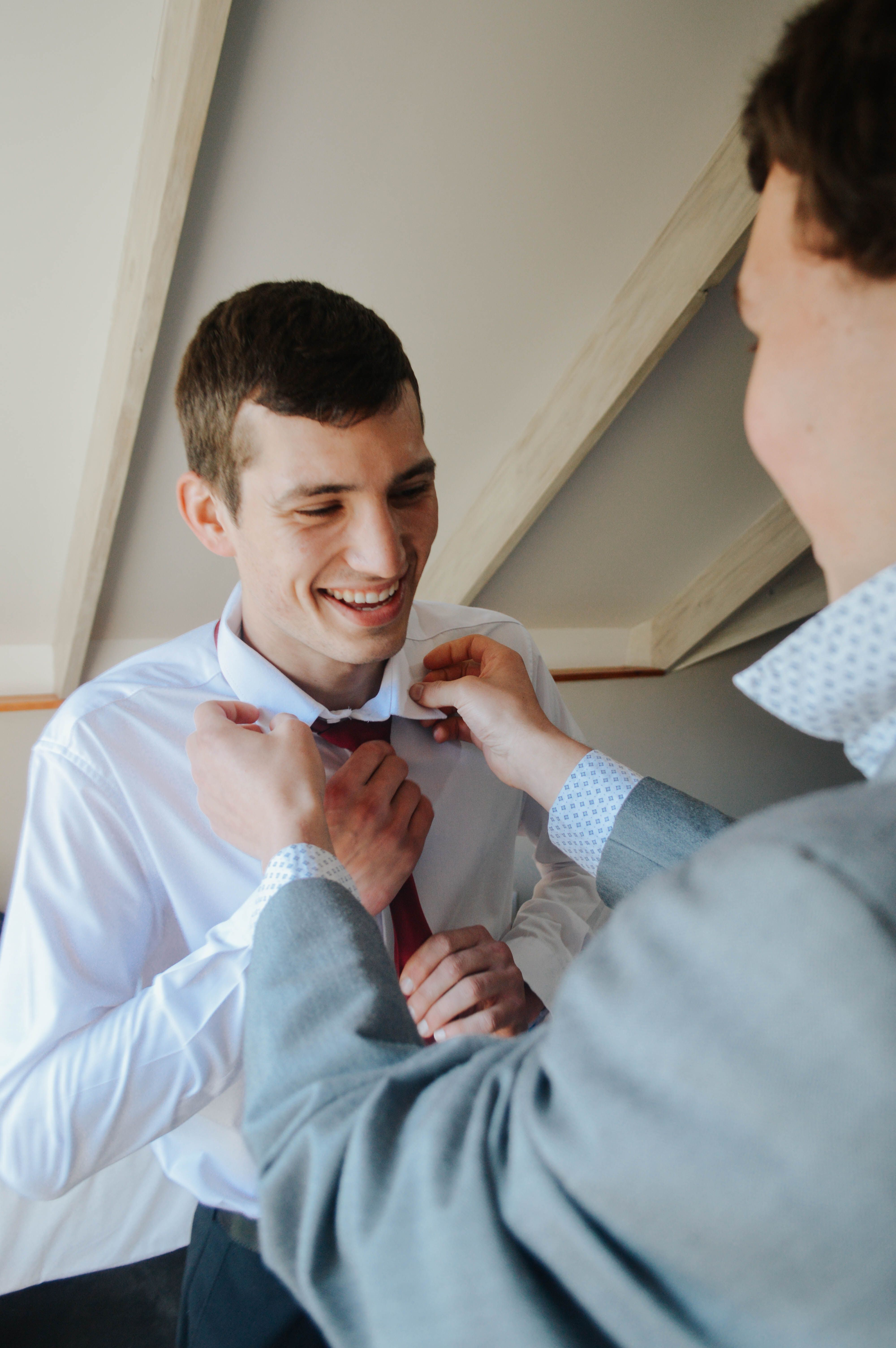 A groom getting ready for his wedding day with assistance from a friend.