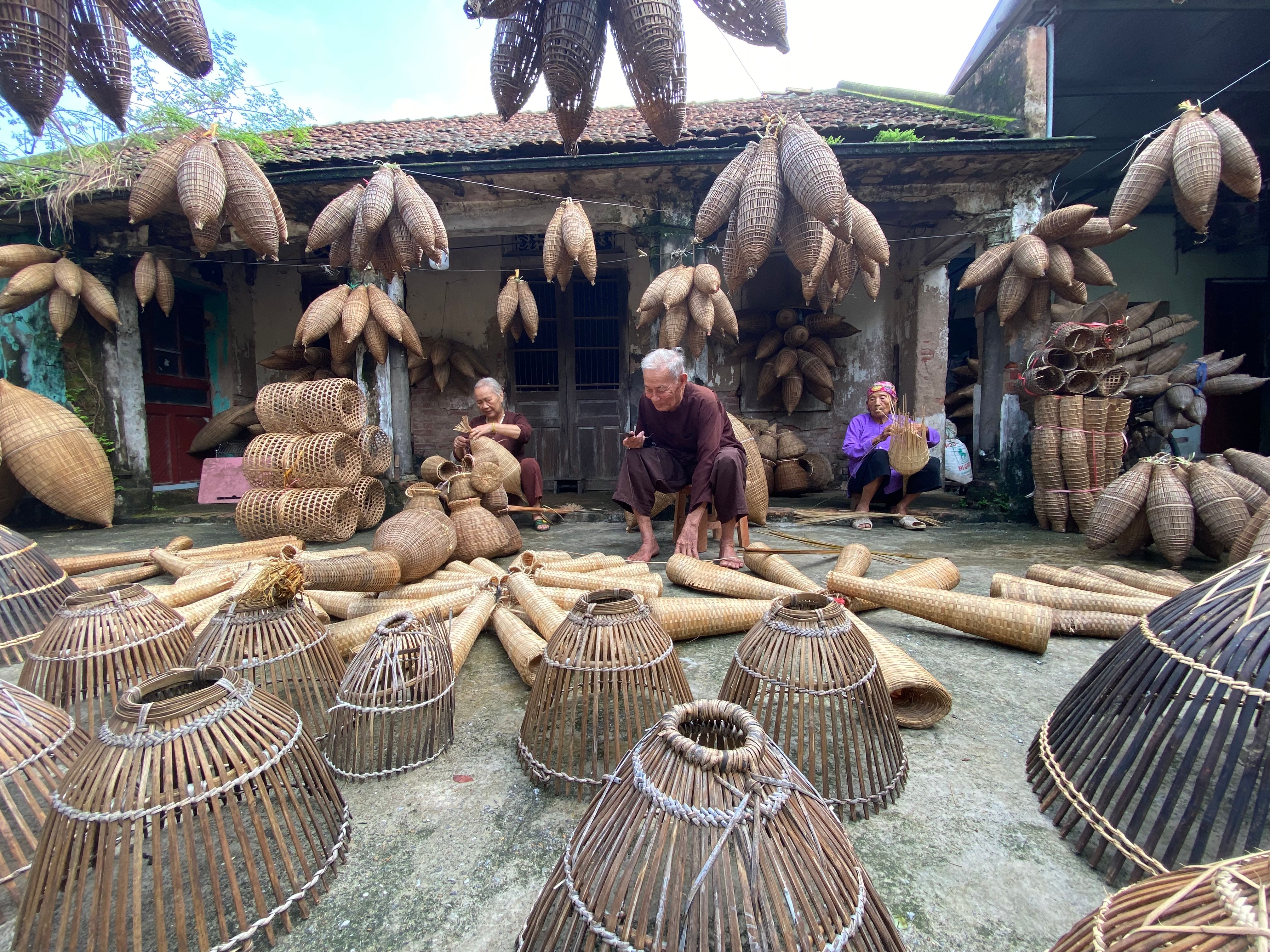 Elderly artisans crafting traditional bamboo baskets in an outdoor setting, surrounded by handcrafted woven items.