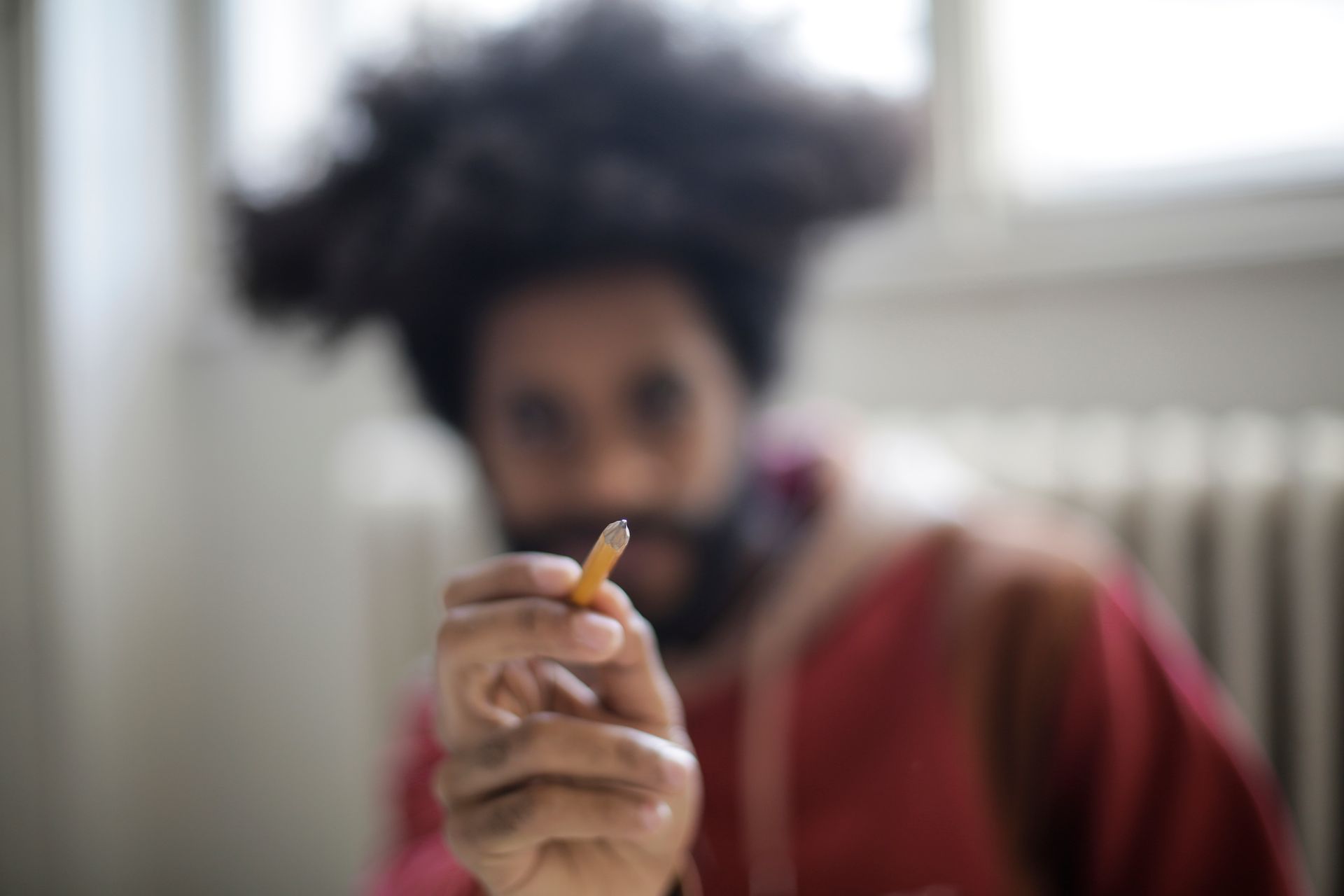Eccentric young male artist showing pencil on blurred background being ready for painting and designing process as concept of imagination and fantasy