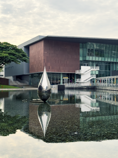 Free Contemporary building with a reflective teardrop sculpture on water. Stock Photo