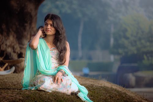 Free A woman in traditional attire sits outdoors in a serene, natural setting. Stock Photo