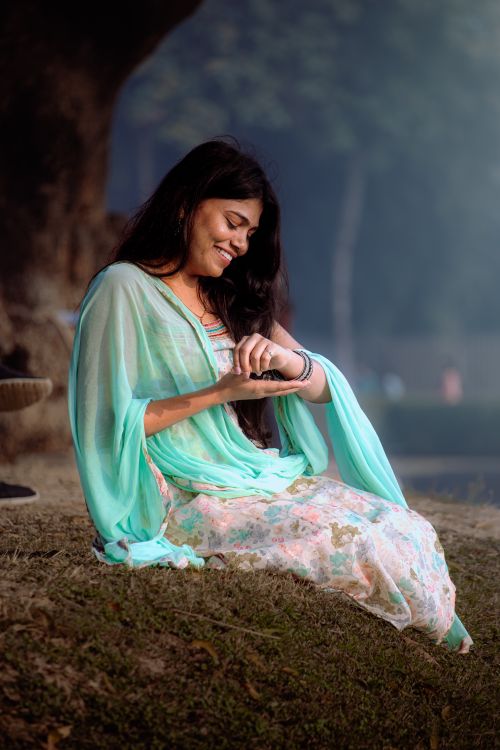 Free A smiling woman in traditional attire enjoys a peaceful moment outdoors. Stock Photo
