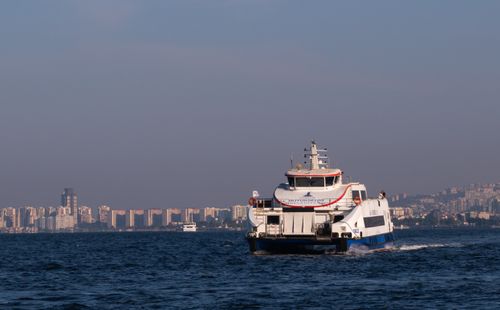 Free Ferry navigating the Aegean Sea with the İzmir city skyline in the background. Stock Photo