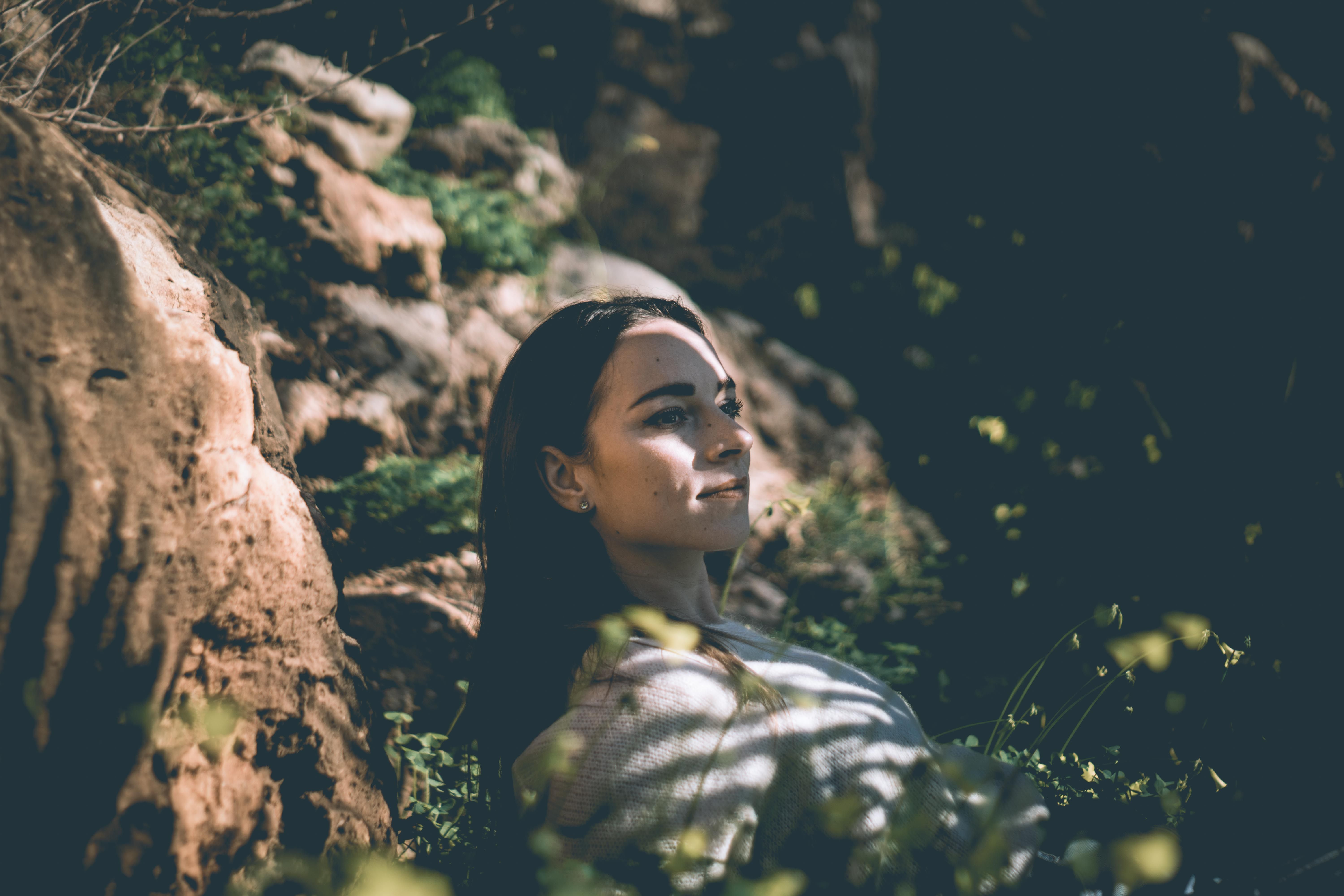 Woman relaxing in nature at Felanitx, enjoying sunlight and tranquility amidst rocky surroundings.