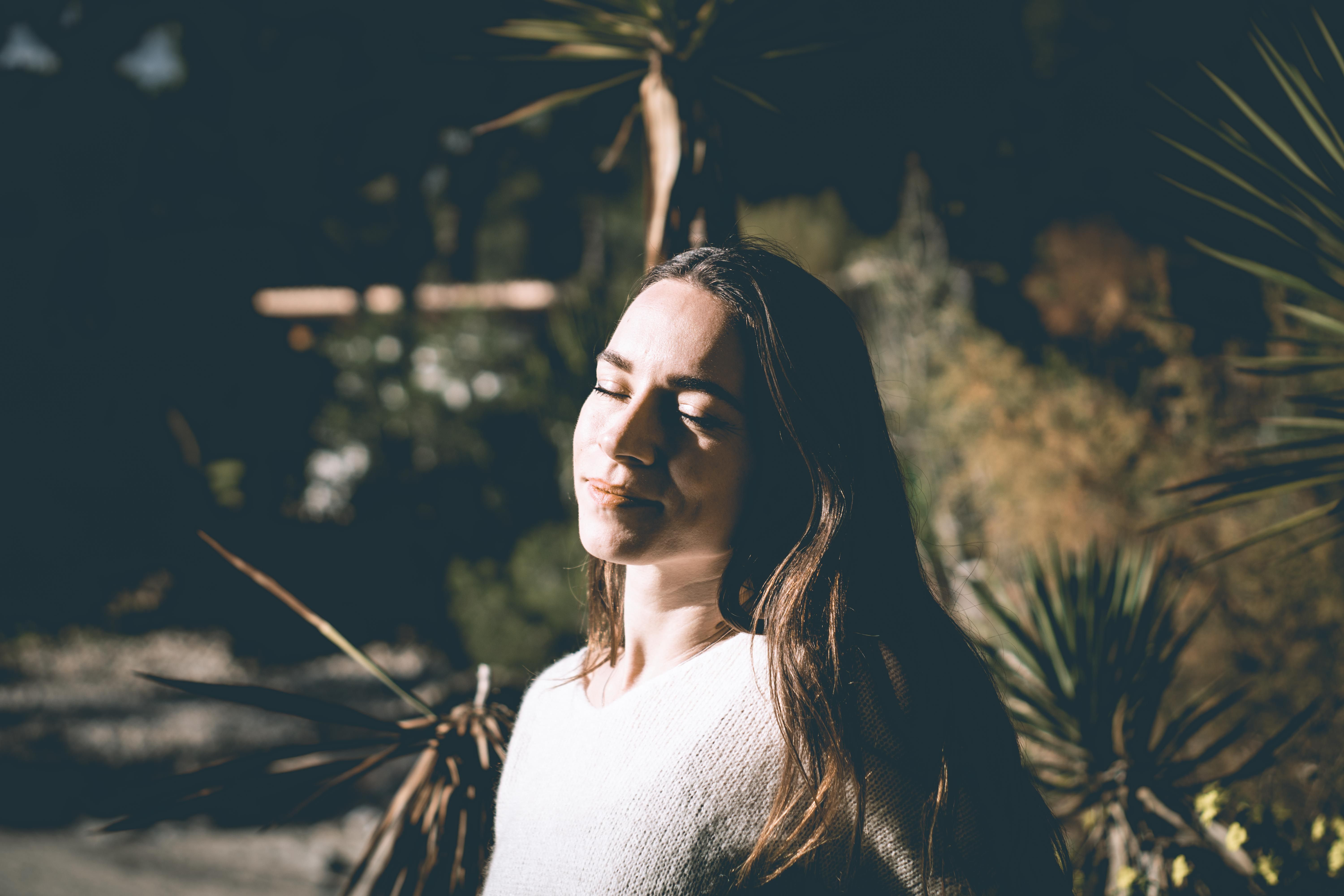 Woman enjoying serene outdoor moment with eyes closed in sunlight, Felanitx, Spain.
