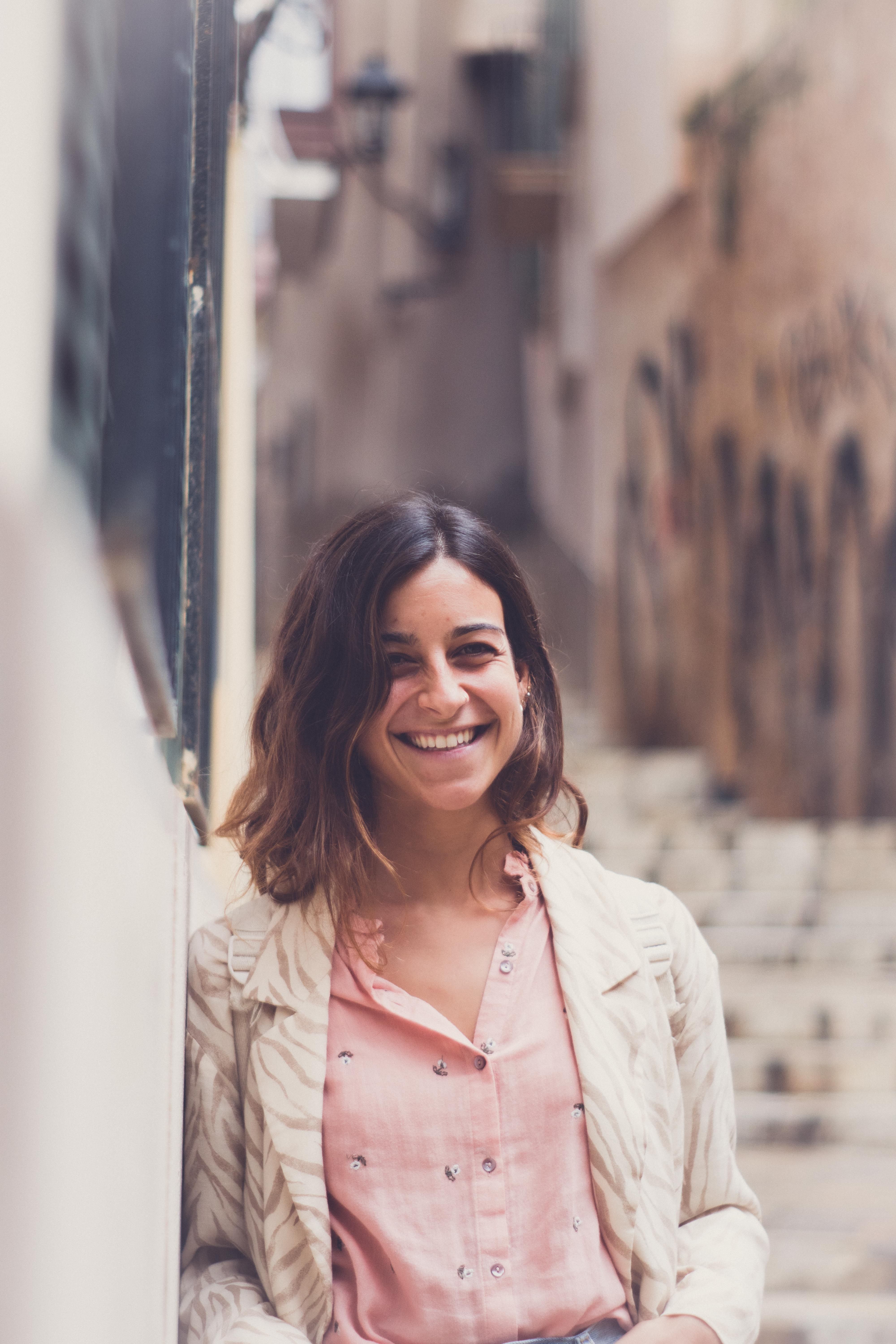 A cheerful woman stands in a charming alley of the Balearic Islands, Spain.