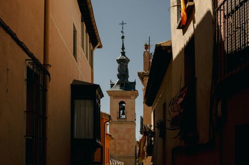 Free A beautiful view of the historic bell tower in Toledo, Spain, framed by traditional buildings. Stock Photo