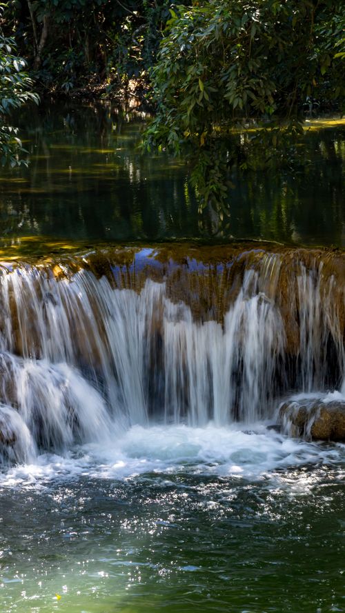 Free Peaceful waterfall cascading in a lush forest in MS, Brazil. Perfect for nature themes. Stock Photo