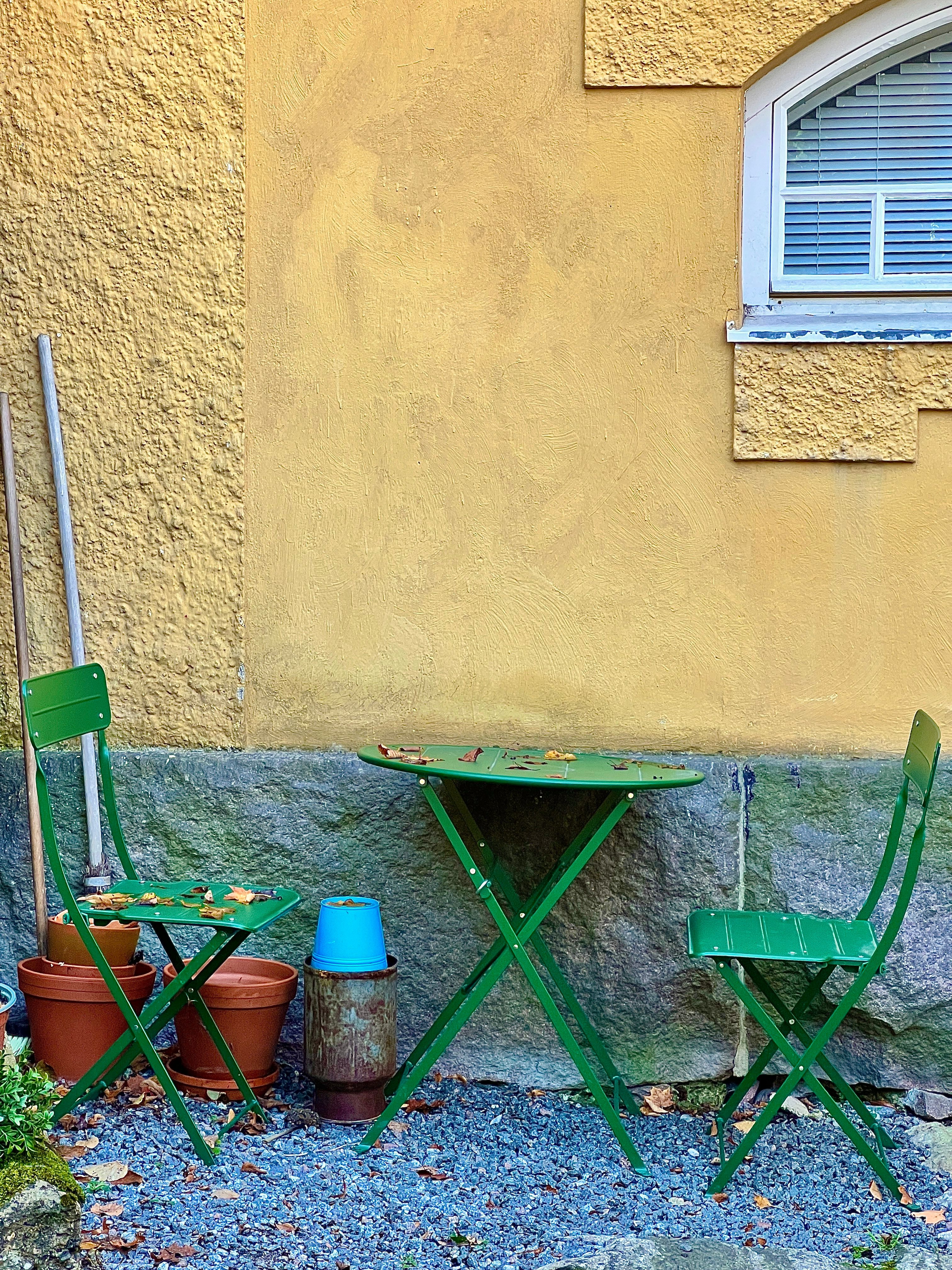 Wall mounted metal vertical garden planter filled with gravel and small flowering plants on a patio privacy wall