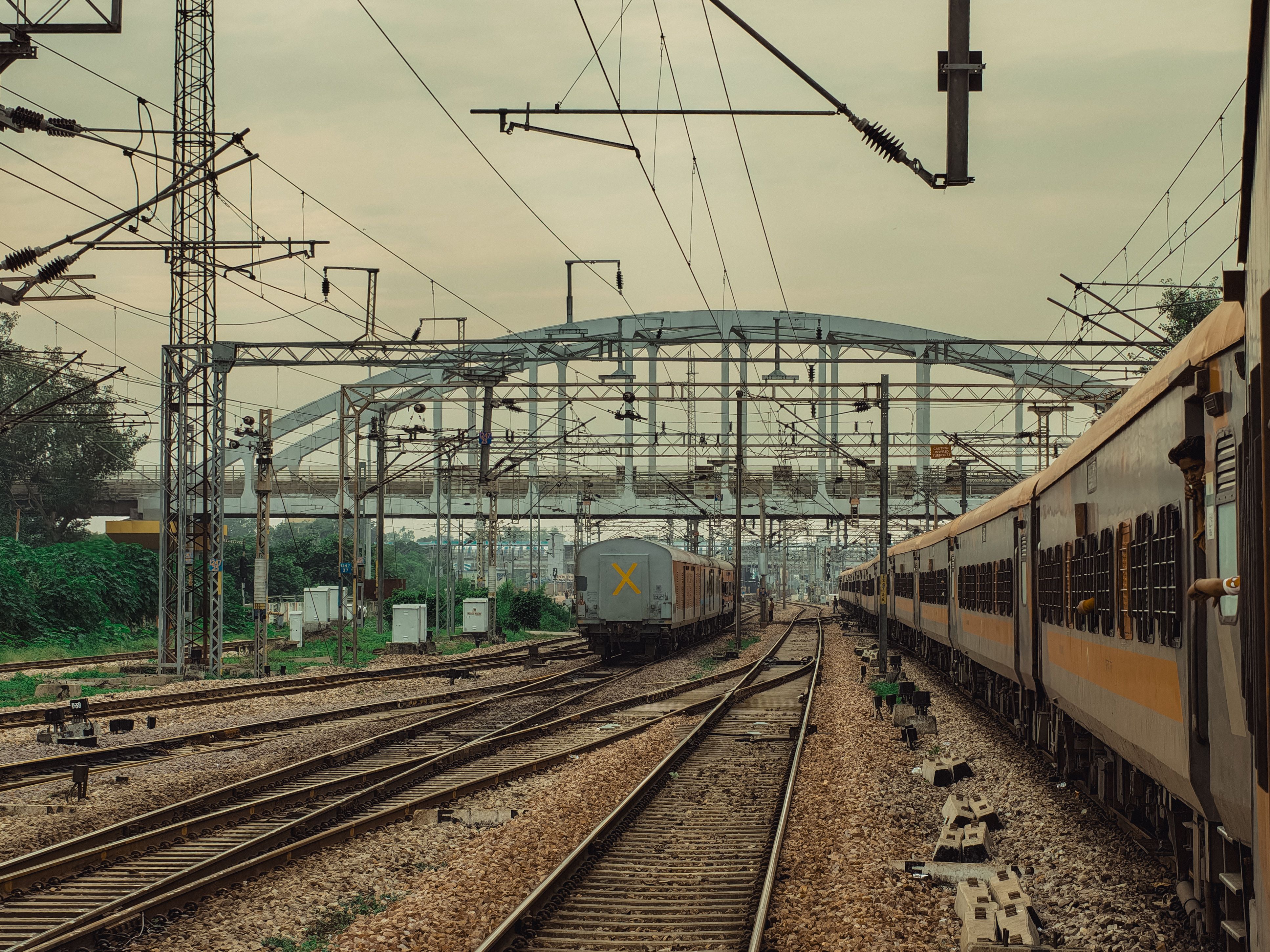Distant view of train tracks and overhead wires under a cloudy sky at a bustling railway junction.