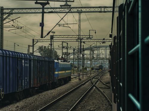 Free View of trains on intersecting railway tracks under a cloudy sky, conveying an industrial atmosphere. Stock Photo
