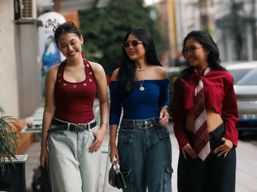Free Three stylish young women walking together on a city street, showcasing trendy fashion. Stock Photo