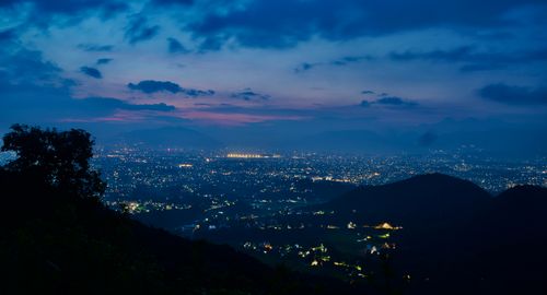 Free A breathtaking view of a city illuminated under the twilight sky, surrounded by hills. Stock Photo