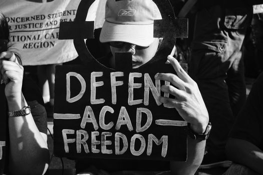 A protestor holds a sign reading 'Defend Acad Freedom' at a rally supporting academic freedom.