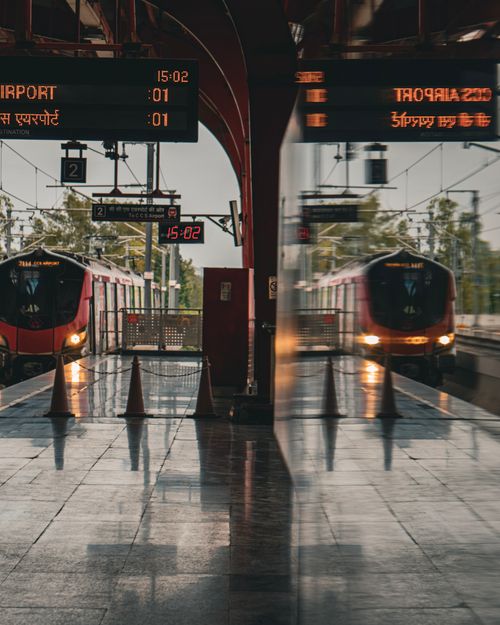 Free A modern train station featuring two trains with reflective surfaces and digital signage. Stock Photo