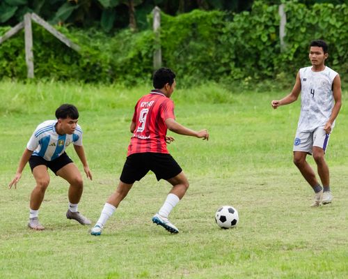 Free Young men playing a lively football match on a grassy field in Myawadi, Myanmar. Stock Photo