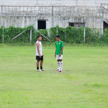Two young men on a football field in Myawadi, Myanmar, discussing strategy.（イメージ）