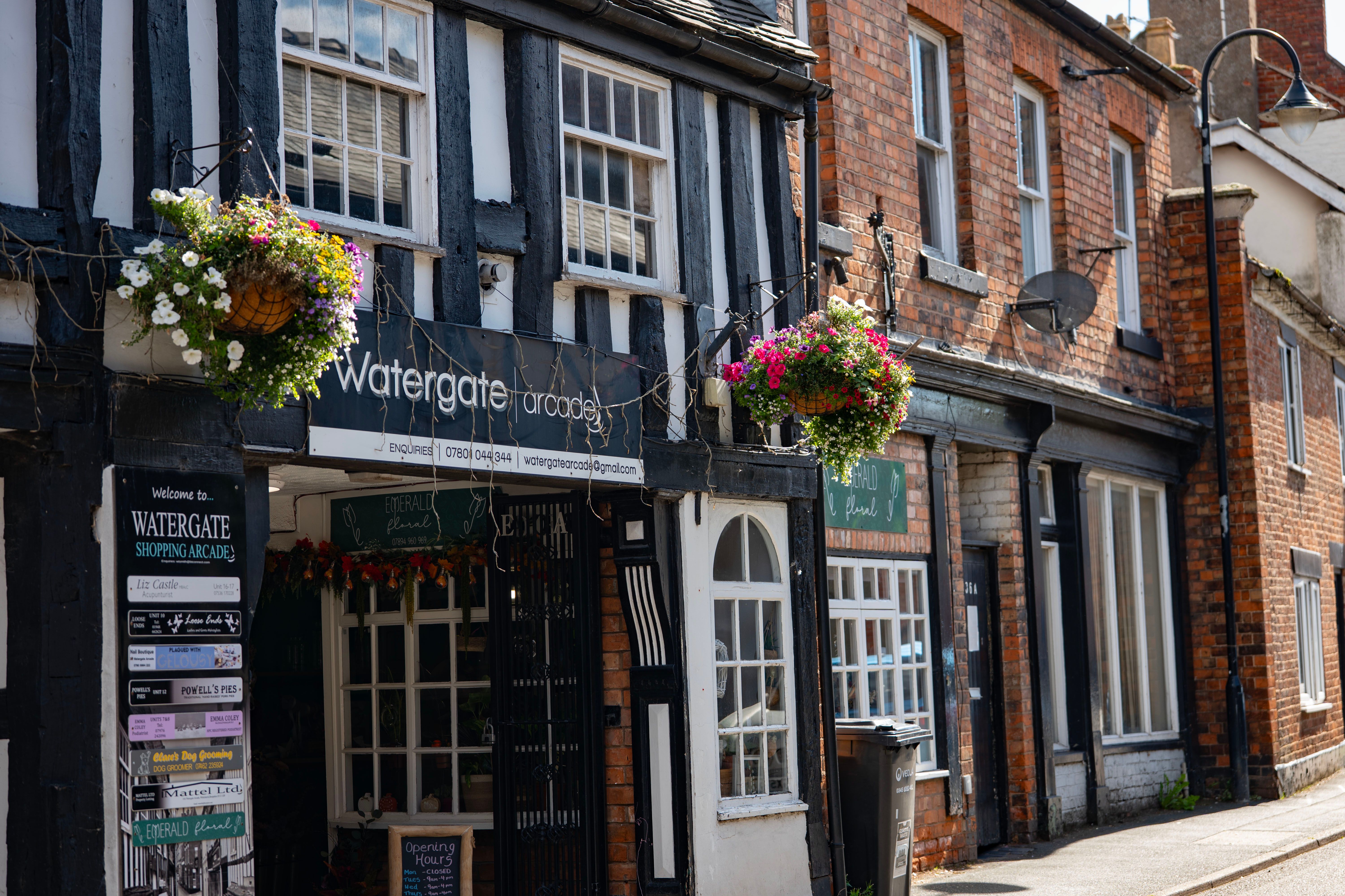 Charming Tudor architecture with flower baskets in Whitchurch, England, on a sunny day.