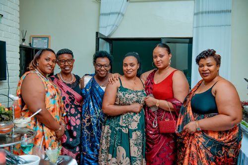 Free A group of smiling women wearing colorful traditional Rwandan dresses at an indoor social event. Stock Photo