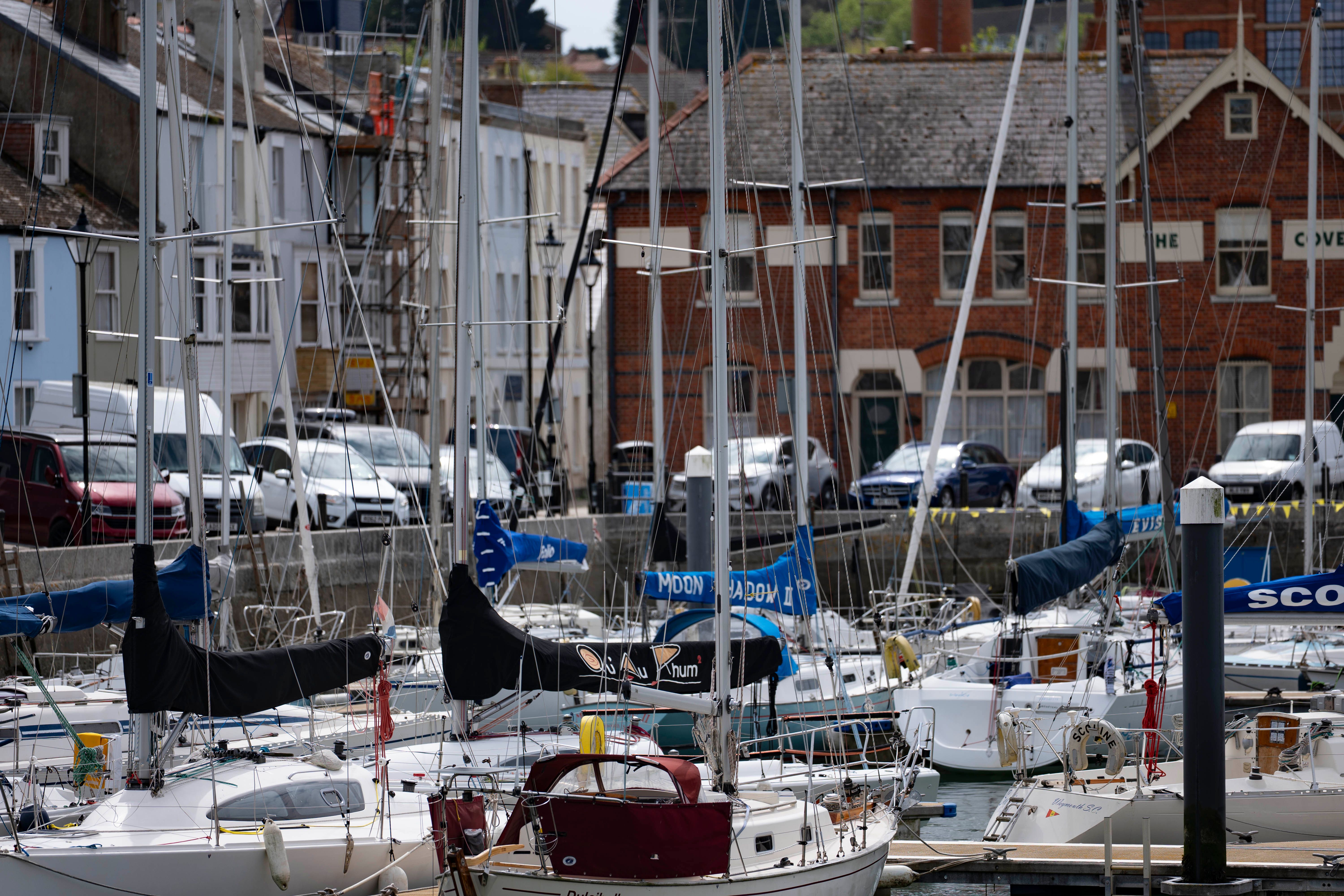 Scenic view of boats docked at Weymouth Harbour, England, with historic brick buildings in the background.