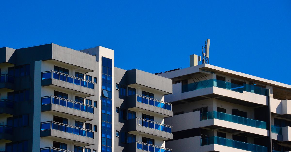 Contemporary high-rise building with balconies set against a vibrant blue sky.