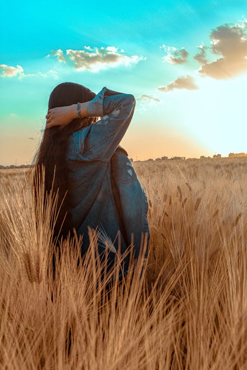 Woman Standing on Grass Field Watching Sunset