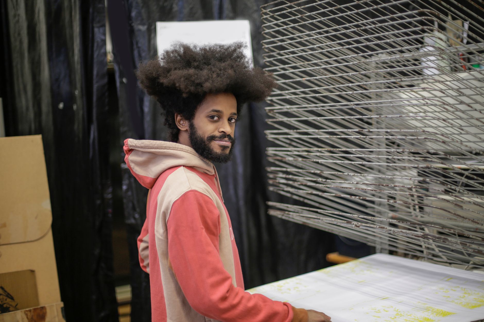 Professionnel du marquage textile dans un atelier de production, entouré de supports en cours de séchage