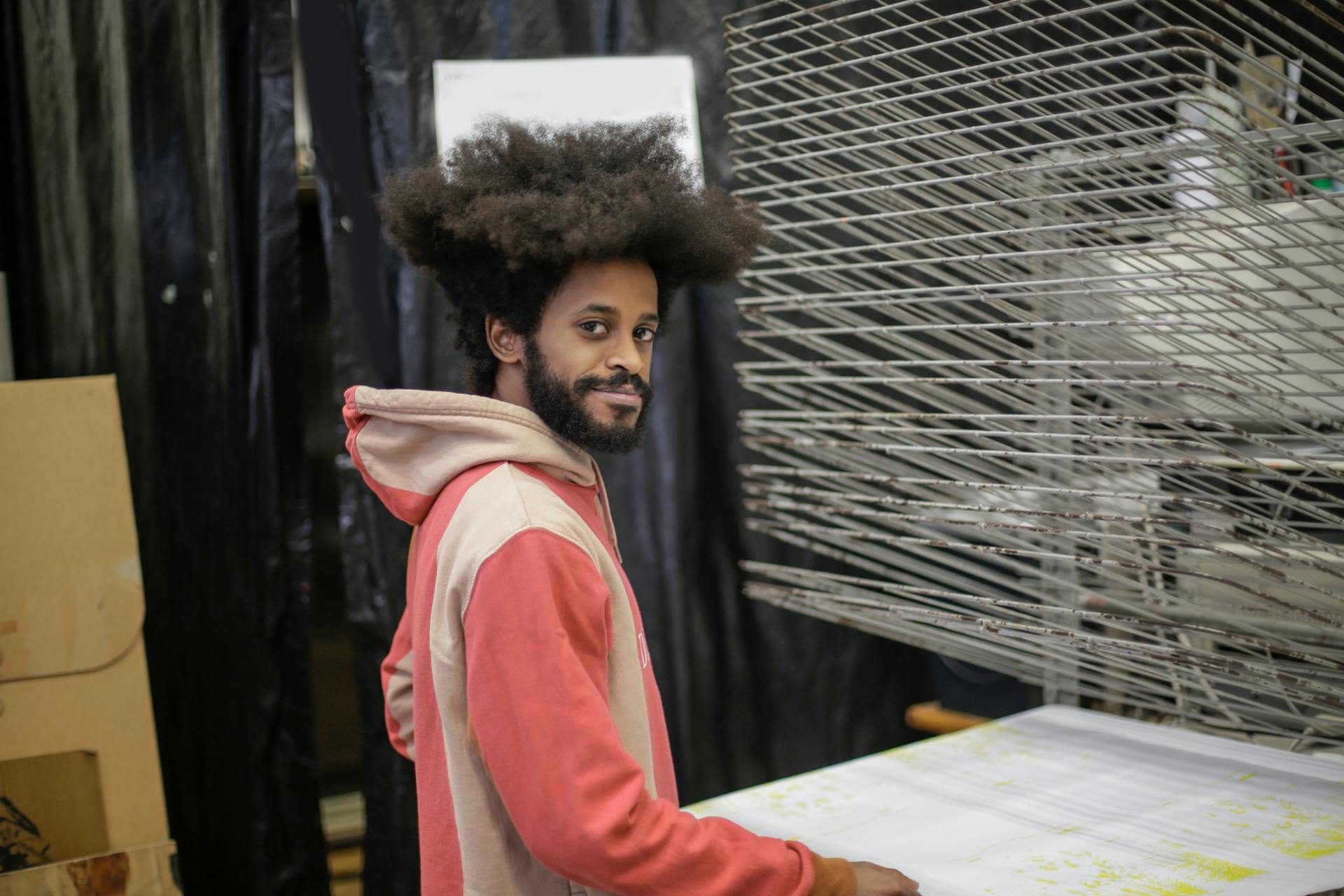 Portrait of a young designer in a workshop, smiling confidently at the camera.