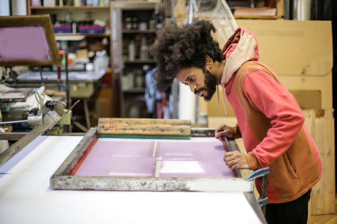 Free Creative young ethnic craftsman working with screen printing in workshop Stock Photo