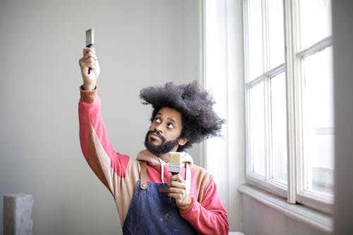 Man Having Fun Holding Two Paintbrushes