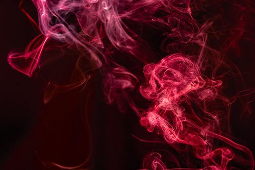 Free Captivating abstract art featuring vivid red smoke swirls on a dark background. Stock Photo