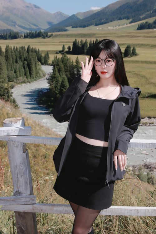 Free Young woman in black outfit posing by a river in a picturesque mountain valley. Stock Photo