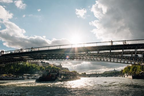 Free Stunning view of a sunlit bridge and cruise on the River Seine with dramatic clouds in Paris, France. Stock Photo