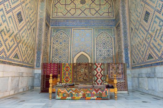 Stunning interior of a mosque in Samarkand, showcasing detailed tilework and vibrant traditional rugs.