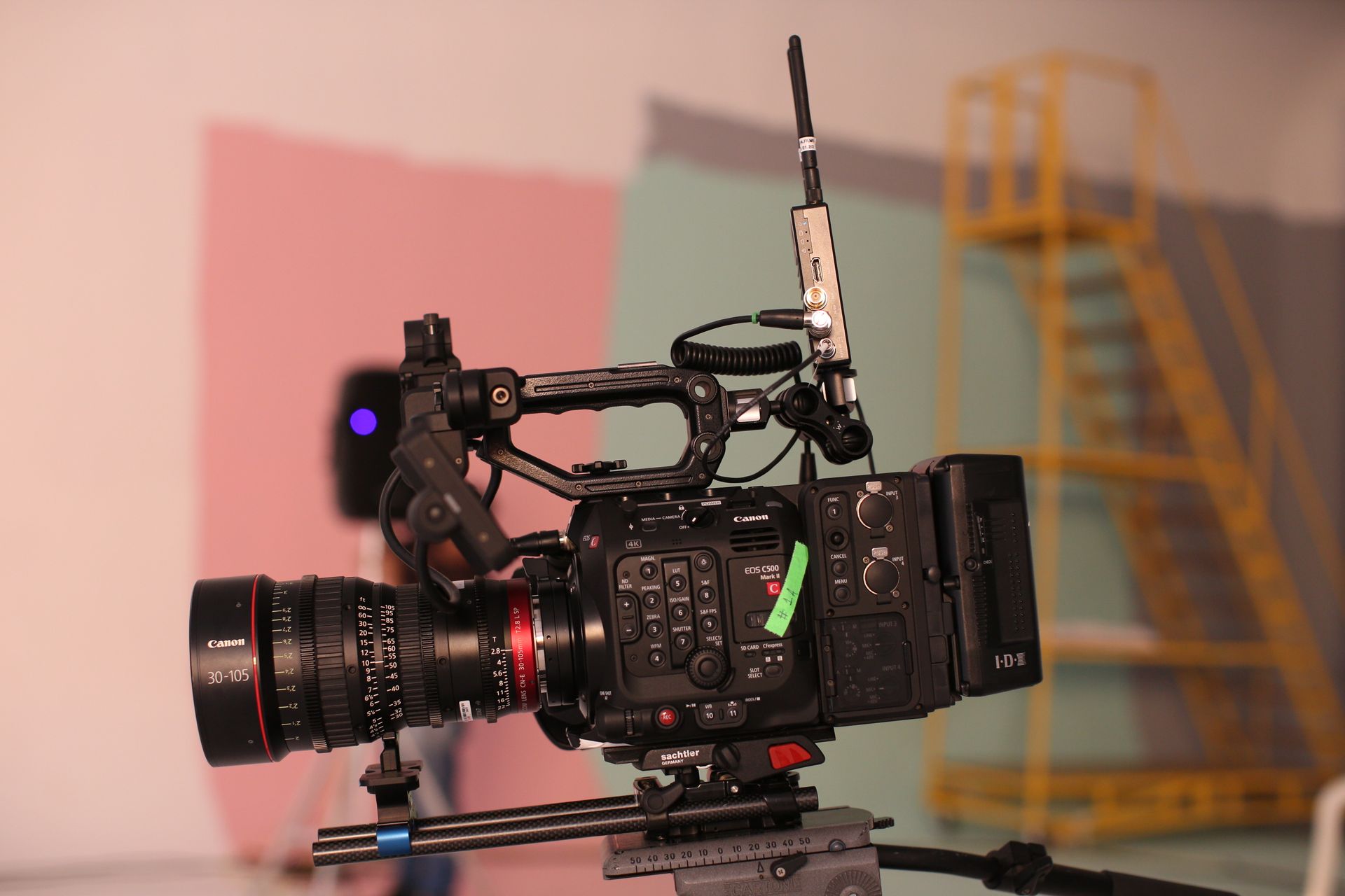 High-end Canon video camera setup in a studio with soft background colors and a ladder.