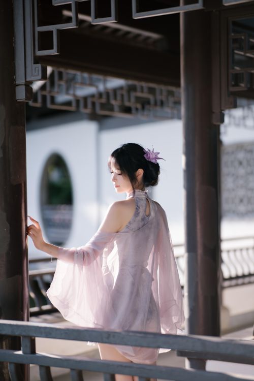 Free A woman in elegant attire poses gracefully in a traditional Asian garden setting. Stock Photo
